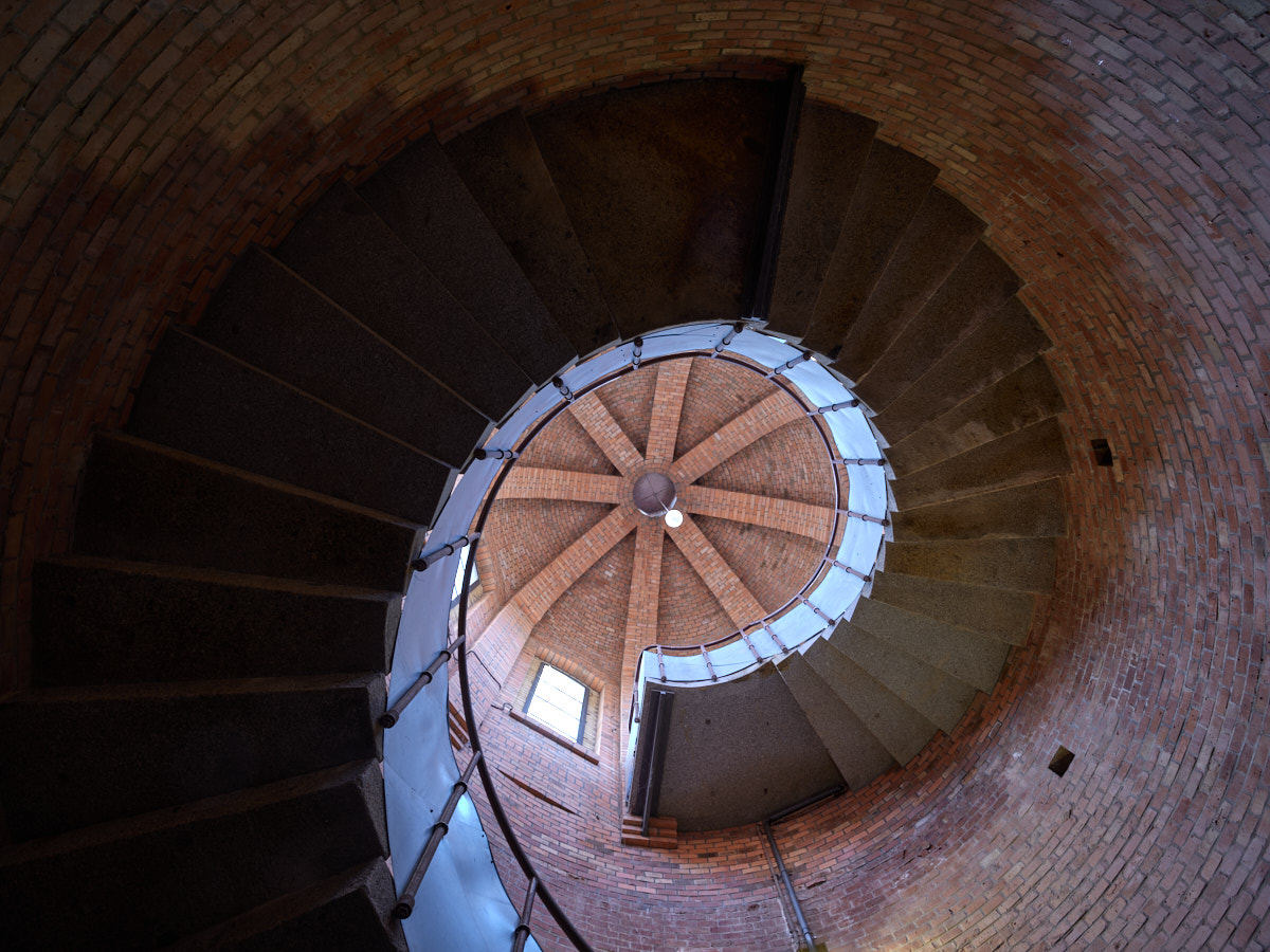Der Blick fällt nach oben in die als Spirale verlaufenden Stufen der Wendeltreppe im Turm.
